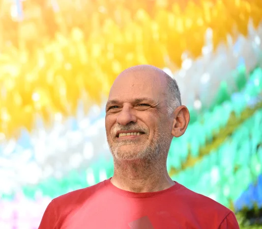 Retrato do Dr. Giancarlo Spizzirri sorrindo diante de um painel colorido
